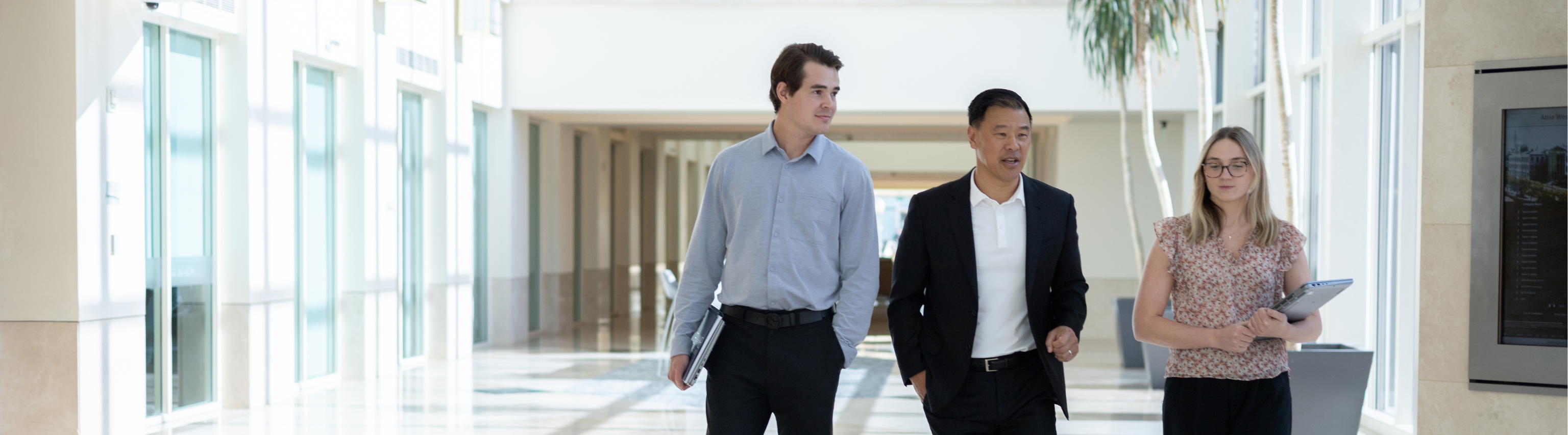 Three co-workers walking in building lobby